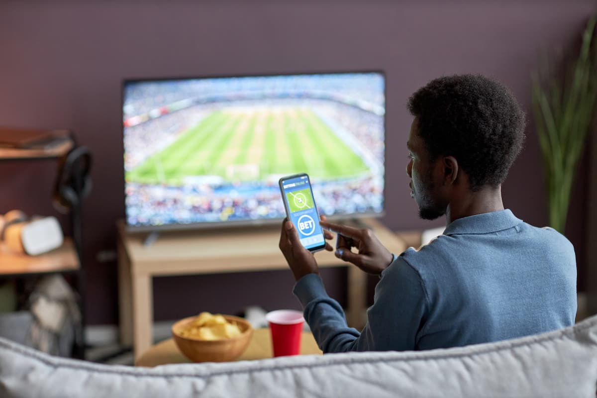 Man holding smartphone with sweeps sports bets app on screen